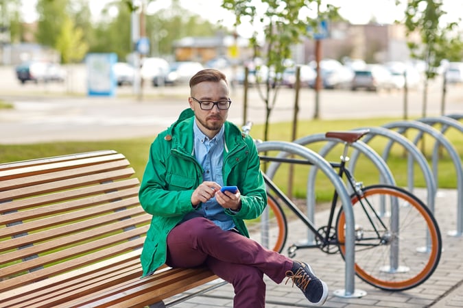 happy young hipster man with smartphone and bike - AdobeStock_87063667 - June 2024 Blog
